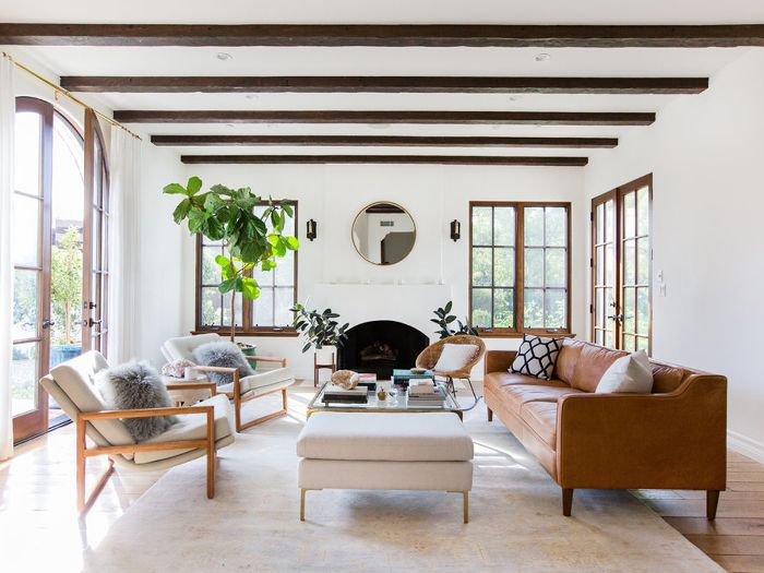 Bright living room with wood beams, fireplace, and warm leather sofa